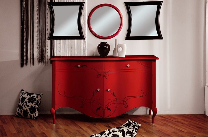 Credenza bombata decorata in arte povera, laccata rossa, con le volute nere dipinte e le specchiere