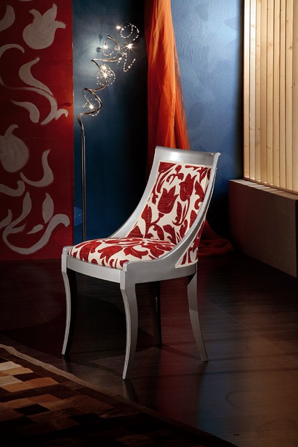 Poltroncina laccata in arte povera, con lo schienale avvolgente tappezzato a fiori rossi