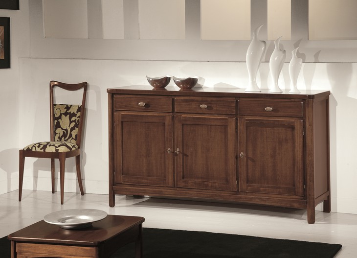 Credenza classica in legno 3 ante, in noce, con 3 cassetti, accanto a una sedia imbottita